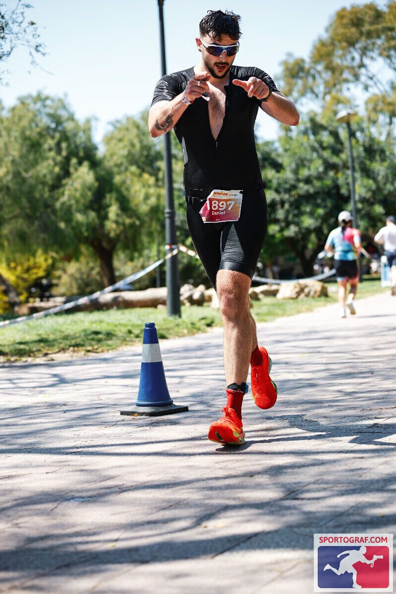 Dan racing in triathlon gear, pointing at the camera mid-run